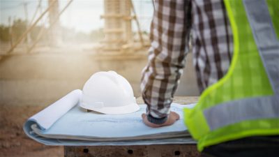 Person at construction site reviewing blueprints